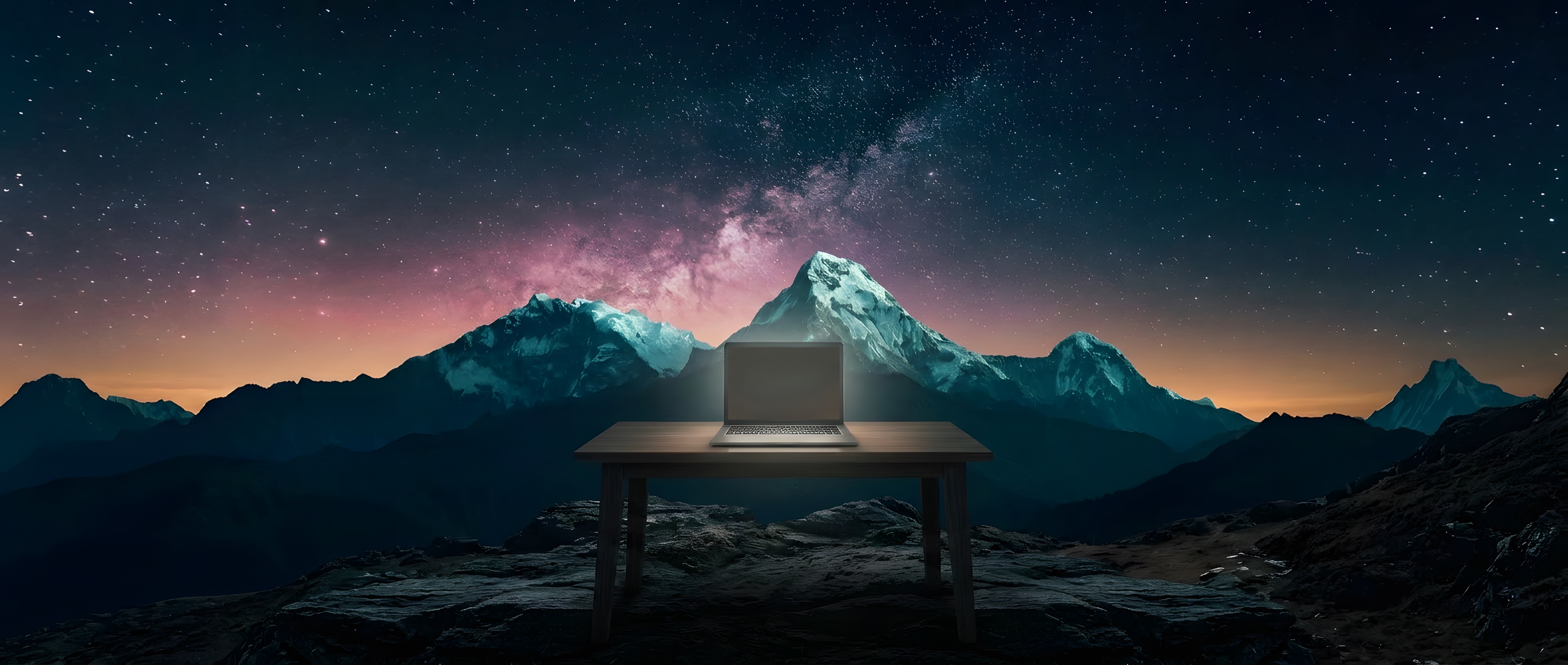 A laptop glowing on a wooden desk at night, alone in front of mountains under a starry sky